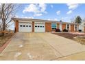 A single story brick home with a two car garage and a driveway at 7412 W 76Th Ave, Arvada, CO 80003