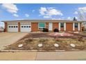 Well-maintained single-story brick home featuring an attached two-car garage and manicured landscaping at 7412 W 76Th Ave, Arvada, CO 80003