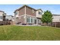 The back of the home features a grassy yard and patio seating area at 242 S Old Hammer Ct, Aurora, CO 80018