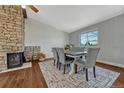 Dining room features wood floors, exposed brick fireplace, neutral colors, and many windows at 18056 E Mansfield Ave, Aurora, CO 80013