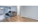 Bright living room featuring wood floors, a gray couch, and access to outdoor balcony at 1585 S Holly St # 109, Denver, CO 80222
