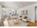 Open living room with hardwood floors, white furniture, and a view into the bright white kitchen at 7555 E 22Nd Ave, Denver, CO 80207