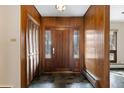 Warm foyer featuring wood paneled walls, slate floors, and a classic wood front door at 5736 S Ivy St, Greenwood Village, CO 80111