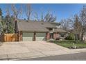 Two-story home showcasing a large driveway, a two-car garage, and partial fence at 6487 W Weaver Ave, Littleton, CO 80123
