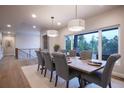 Dining room with a view of the tree tops and gray upholstered chairs that seat eight people around a wood table at 17548 Colonial Park Dr, Monument, CO 80132