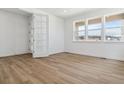 Bright bedroom with white walls and trim, wood floors, recessed lights, and double doors at 8686 Pennycress Dr, Littleton, CO 80125