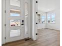 Bright foyer with wood floors, modern white door with windows, and view into the adjacent room at 8686 Pennycress Dr, Littleton, CO 80125