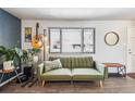 Bright living room with wood floors, a plush green sofa, and a large window offering pleasant views at 8898 W Harvard Pl, Lakewood, CO 80227