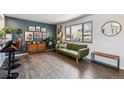 Stylish living room featuring a blue accent wall, wood floors, and large windows that bring in natural light at 8898 W Harvard Pl, Lakewood, CO 80227