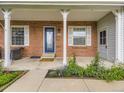Inviting front porch with brick accents, white columns, and a decorative blue door at 5456 E Briarwood Pl, Centennial, CO 80122