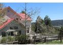 Backyard view of a charming deck and exterior elevation with a red roof, with a mountainous landscape beyond at 28650 Cavan Ln, Evergreen, CO 80439