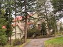 Charming exterior view of a home with a red roof, surrounded by lush trees and a paved driveway at 28650 Cavan Ln, Evergreen, CO 80439