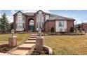 Charming brick and white home featuring a brick walkway with vintage lamp posts and lush green lawn at 9188 Buck Hill Dr, Highlands Ranch, CO 80126
