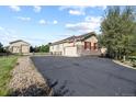 View of a house with an asphalt driveway and an American flag, accented by red window shutters and stone veneer at 42340 Kingsmill Cir, Elizabeth, CO 80107