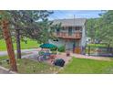 Two story home featuring a deck and patio with seating, bbq, and fireplace at 4724 Hopi Rd, Indian Hills, CO 80454