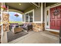 Inviting front porch featuring stone pillars, comfortable seating, a wood table, and a red front door at 28495 La Donna Vista Ln, Elizabeth, CO 80107