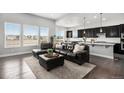 Open-concept living room with dark hardwood floors, large windows, and a comfortable leather sectional sofa at 10114 Atlanta St, Parker, CO 80134