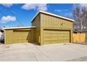 Spacious yellow detached garage with two bays and a basketball hoop against a bright blue sky at 5350 E 66Th Way, Commerce City, CO 80022