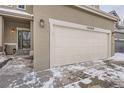 Attached two-car garage with white door and snowy ground at 12460 S Hollow Creek Ct, Parker, CO 80134