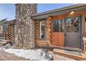 Charming log cabin entrance with a stone chimney, wooden door, and a welcoming 'welcome' mat at 10439 Christopher Dr, Conifer, CO 80433