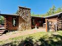 Inviting log cabin featuring a prominent stone chimney and landscaped walkway to the entrance at 10439 Christopher Dr, Conifer, CO 80433