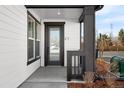 Modern front door of the townhome, with a dark frame, clear glass, and a covered porch with black support beams at 8530 W 52Nd Ave # C1, Arvada, CO 80002