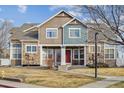 Two-story townhome featuring stone accents, a red front door, and a well-maintained front lawn at 13271 Holly St # D, Thornton, CO 80241