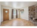 Bright living room featuring a stone fireplace, hardwood floors, and a diamond-paned front door at 4591 S Pennsylvania St, Englewood, CO 80113