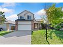 Attractive home featuring a two-car garage, brick accents, and a beautifully maintained front lawn at 2430 S Halifax Way, Aurora, CO 80013