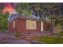 Classic brick home with large window providing ample natural light, showcasing a tranquil evening scene at 4624 W Virginia Ave, Denver, CO 80219