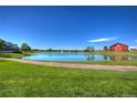 Scenic view of a peaceful pond and lush green lawn in front of a red barn at 10451 Truckee St # 2D, Commerce City, CO 80022