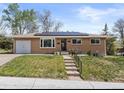 Charming brick home with a well-manicured lawn and solar panels installed on the roof at 4102 W Eastman Ave, Denver, CO 80236