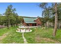 Beautiful log home with a green roof surrounded by a lovely fire pit area at 16861 Wrangler Trl, Littleton, CO 80127