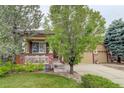 Beautiful home with a well-manicured lawn, mature trees, and a charming front porch at 15372 E 117Th Ave, Commerce City, CO 80022