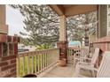 Inviting front porch featuring brick accents, white railings, and seating area at 15372 E 117Th Ave, Commerce City, CO 80022