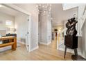 Inviting foyer with light wood floors, modern light fixture, and an elegant sculpture near the staircase at 6334 N Dayton Way, Denver, CO 80238