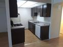 A kitchen with laminate floors, a sink and dishwasher, and a gas range with dark cabinetry at 10772 E Exposition Ave Ave # 342, Aurora, CO 80012