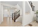 Open-concept foyer featuring elegant wood floors, staircase with dark wood railing, and white trim at 16345 Milwaukee St, Thornton, CO 80602