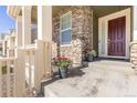 Inviting front porch enhanced by stone accents, decorative plants, and a stylish front door at 16345 Milwaukee St, Thornton, CO 80602