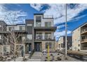 Contemporary three-story townhome with balcony and landscaped front yard at 16551 Peak Way, Broomfield, CO 80023
