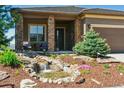 Inviting home exterior with a charming stone porch and beautifully landscaped yard with a tranquil water feature at 438 Galaxy Dr, Castle Rock, CO 80108