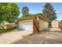 Side view of the residence with an attached white two-car garage and wooden fence at 2531 S Hoyt Ct, Lakewood, CO 80227