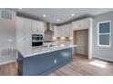Modern kitchen boasts white cabinets, stainless steel appliances, and a large gray island at 8581 Eckley St, Littleton, CO 80125