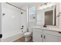 Bright bathroom features a shower-tub combo, white tile, and vanity with storage space and black hardware at 1300 Sienna Peak Cir, Erie, CO 80516