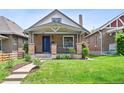 Charming brick home with a gabled roof, covered front porch, blue front door and well-manicured lawn at 3316 N Columbine St, Denver, CO 80205