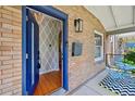Inviting front porch with a blue door, brick facade, patterned wall paper, and modern outdoor light fixture at 3316 N Columbine St, Denver, CO 80205