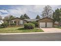 Lovely brick home with a two-car garage, lush green lawn, and mature trees at 4114 S Niagara Way, Denver, CO 80237