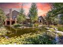 Scenic pond with blooming lily pads and the home's exterior under a vibrant sunset sky, creating a tranquil setting at 8361 Piney Creek Rd, Parker, CO 80138