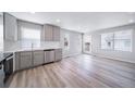 An open concept kitchen and dining area with stainless steel appliances and light hardwood flooring at 46566 Avery Ln, Bennett, CO 80102