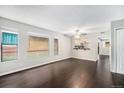 Bright and spacious living room with dark wood floors, fresh paint, large windows, and a pass-through to the kitchen at 1273 S Crystal Way, Aurora, CO 80012